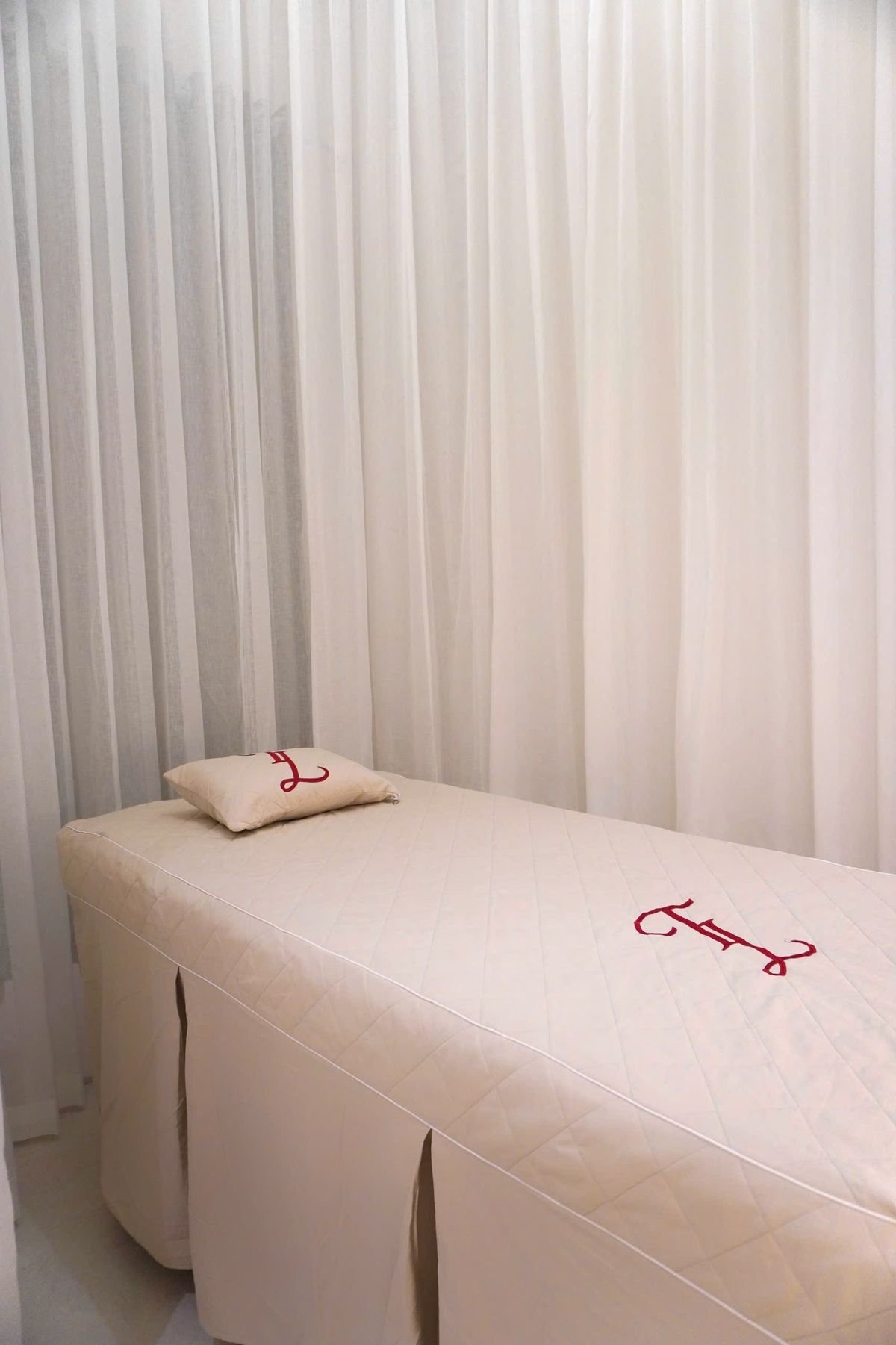 A calm, minimalist spa treatment bed dressed with soft white linen at Ganga Spa